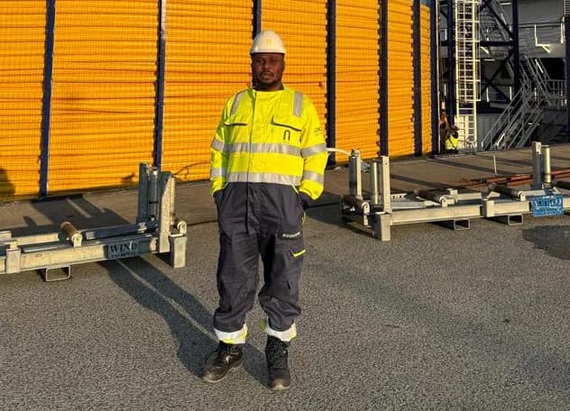 Olaniyi Oluwasegun Ishola wearing a hard hat and high-visibility workwear on a vessel's deck
